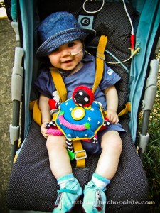 Dominic smiling in his pram with a nasogastric feeding tube